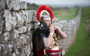 Съвременен човек похава бургер, облечен като римски легионер. Изображение: English Heritage