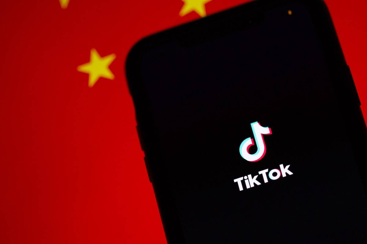 TikTok, работещ на iPhone. Зад него е изобразено знамето на Китай.