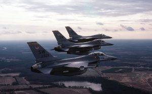 Изглед от въздуха отдясно на три самолета F-16 Fighting Falcon в ешелонна формация. Самолетът на преден план е въоръжен с ракета AIM-9 Sidewinder, монтирана на върха на крилото. Снимка: NARA & DVIDS Public Domain Archive