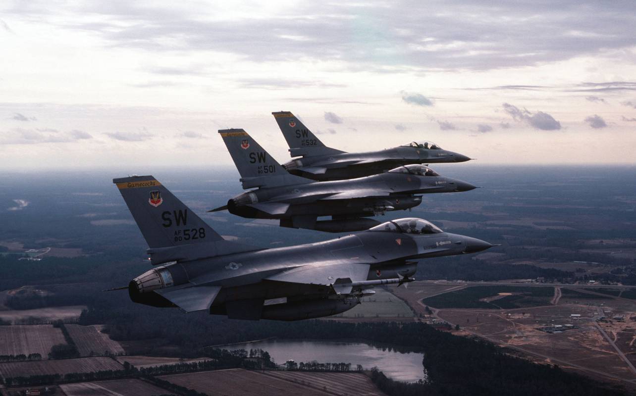Изглед от въздуха отдясно на три самолета F-16 Fighting Falcon в ешелонна формация. Самолетът на преден план е въоръжен с ракета AIM-9 Sidewinder, монтирана на върха на крилото. Снимка: NARA & DVIDS Public Domain Archive