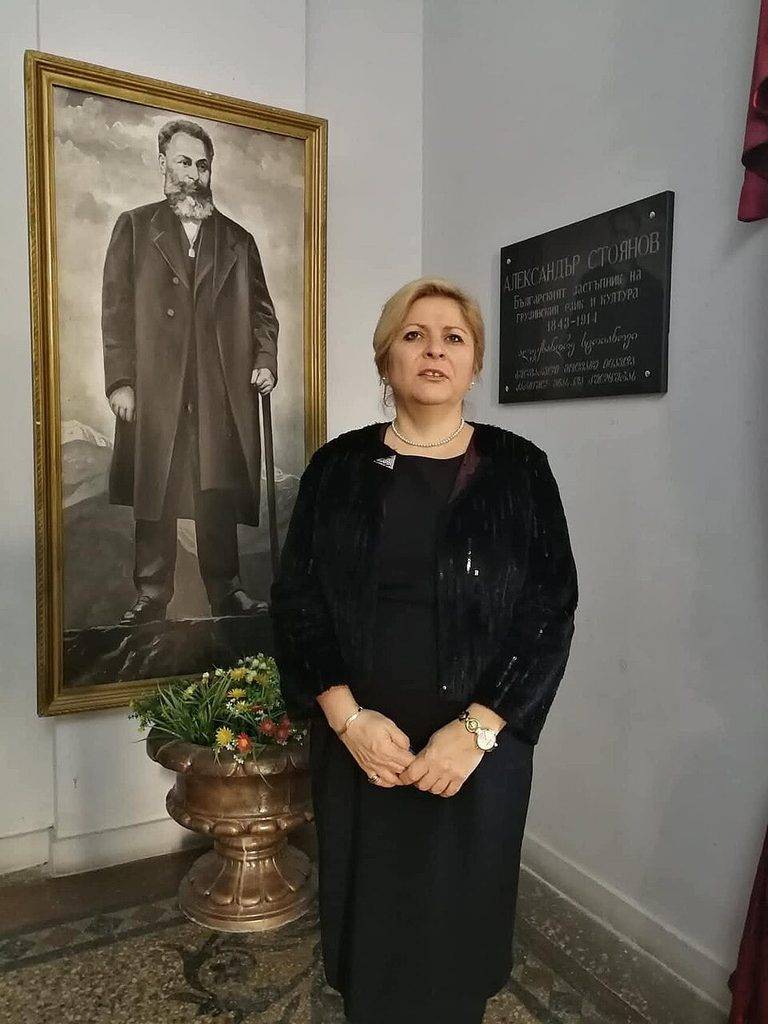 Бившият посланик на България Десислава Иванова пред портрета и плакета в памет на Александър Стоянов, паметта за когото бе спасена от Райна Белева.